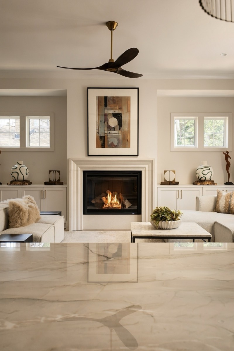 Living room with a lit fireplace seen across a polished marble island