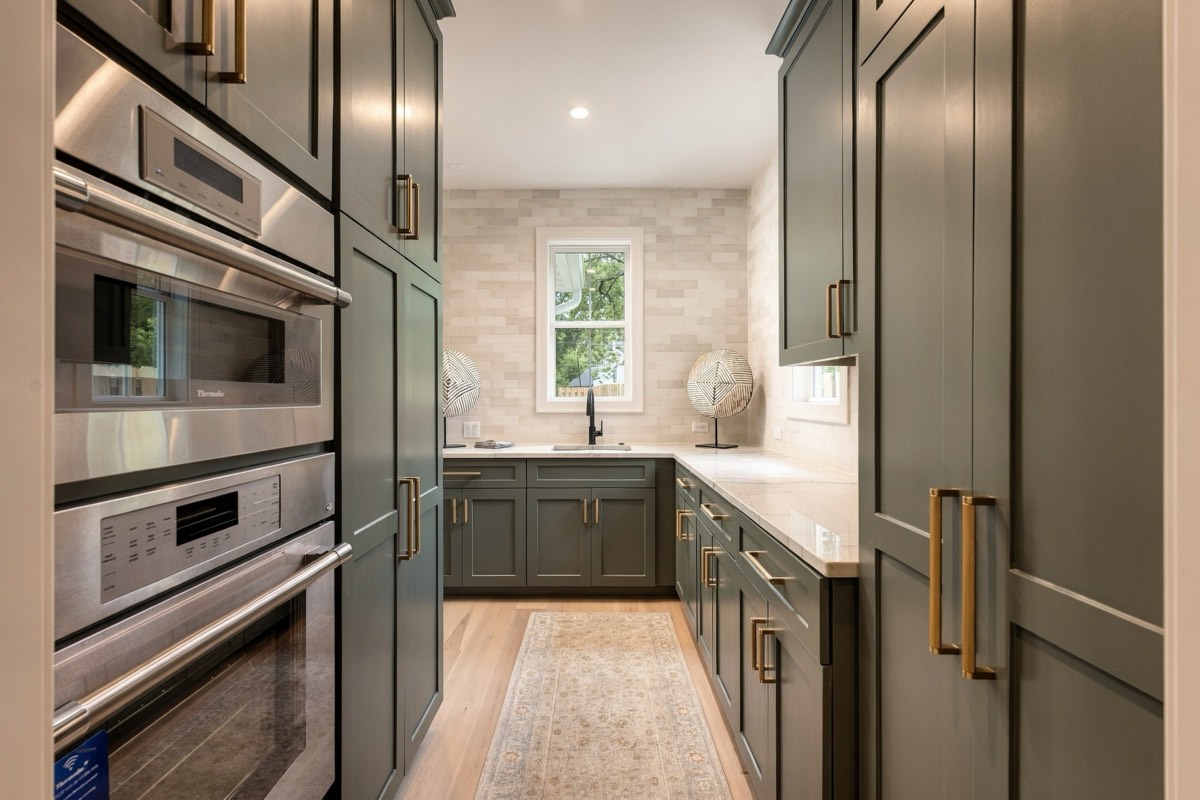 Galley kitchen with deep green cabinetry and brass hardware