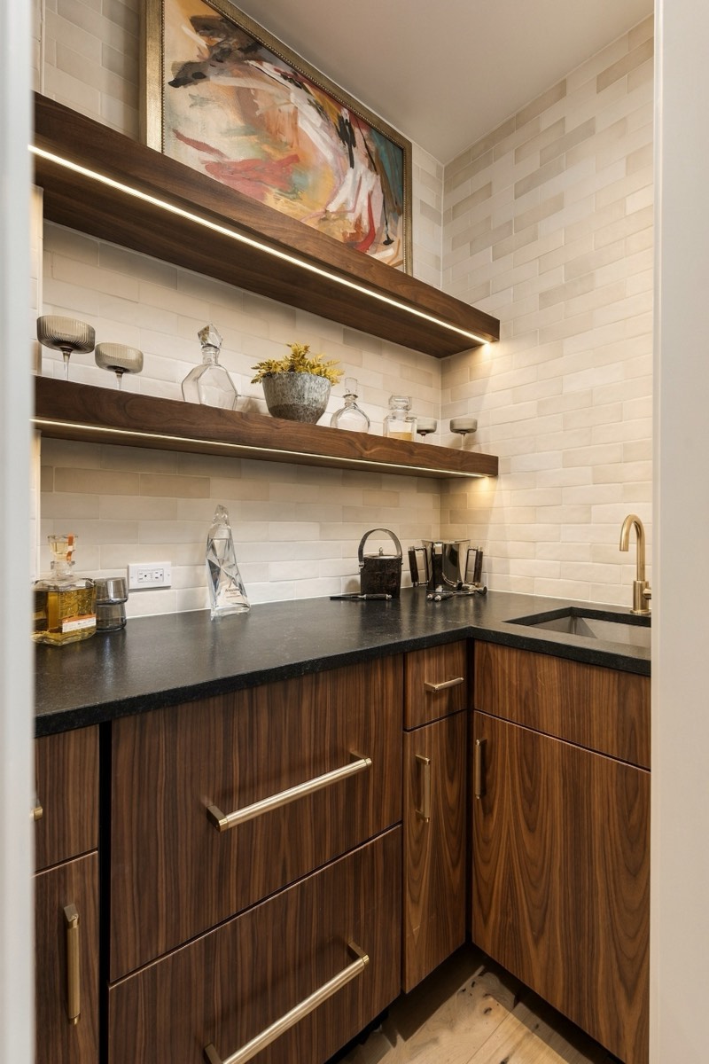 Walnut wet bar with lit shelving and a honed stone counter