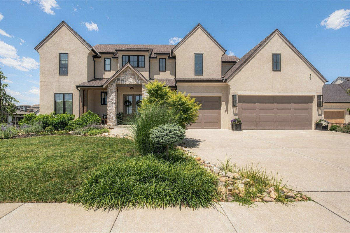 Stucco and stone two-story home with manicured front landscaping