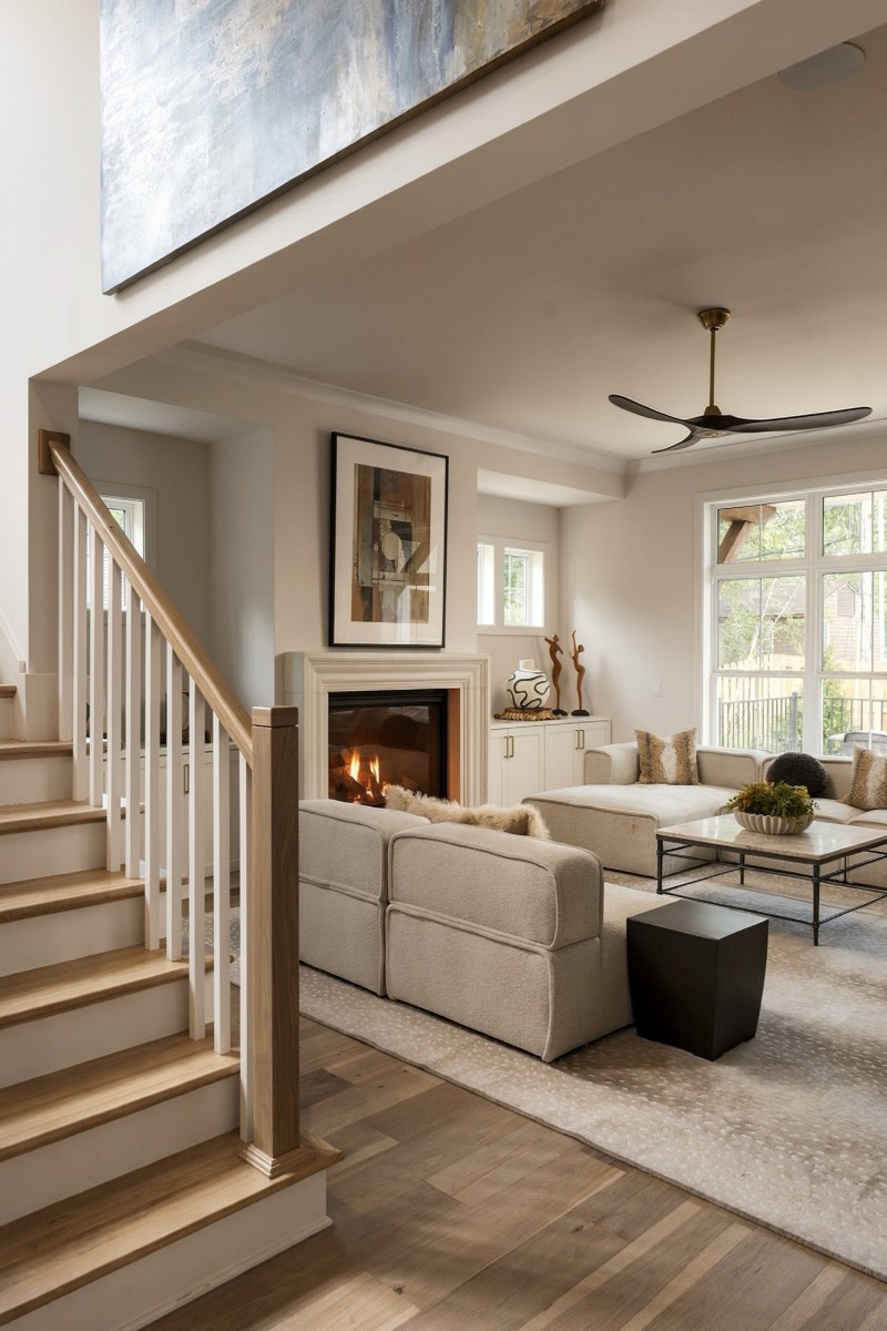 Open living room viewed past a white oak staircase