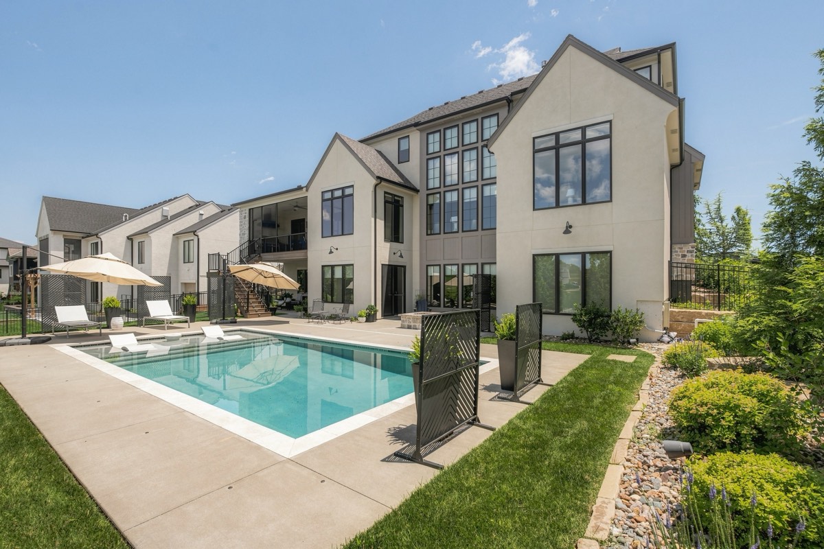 Poolside view of a modern stucco home with black-framed windows