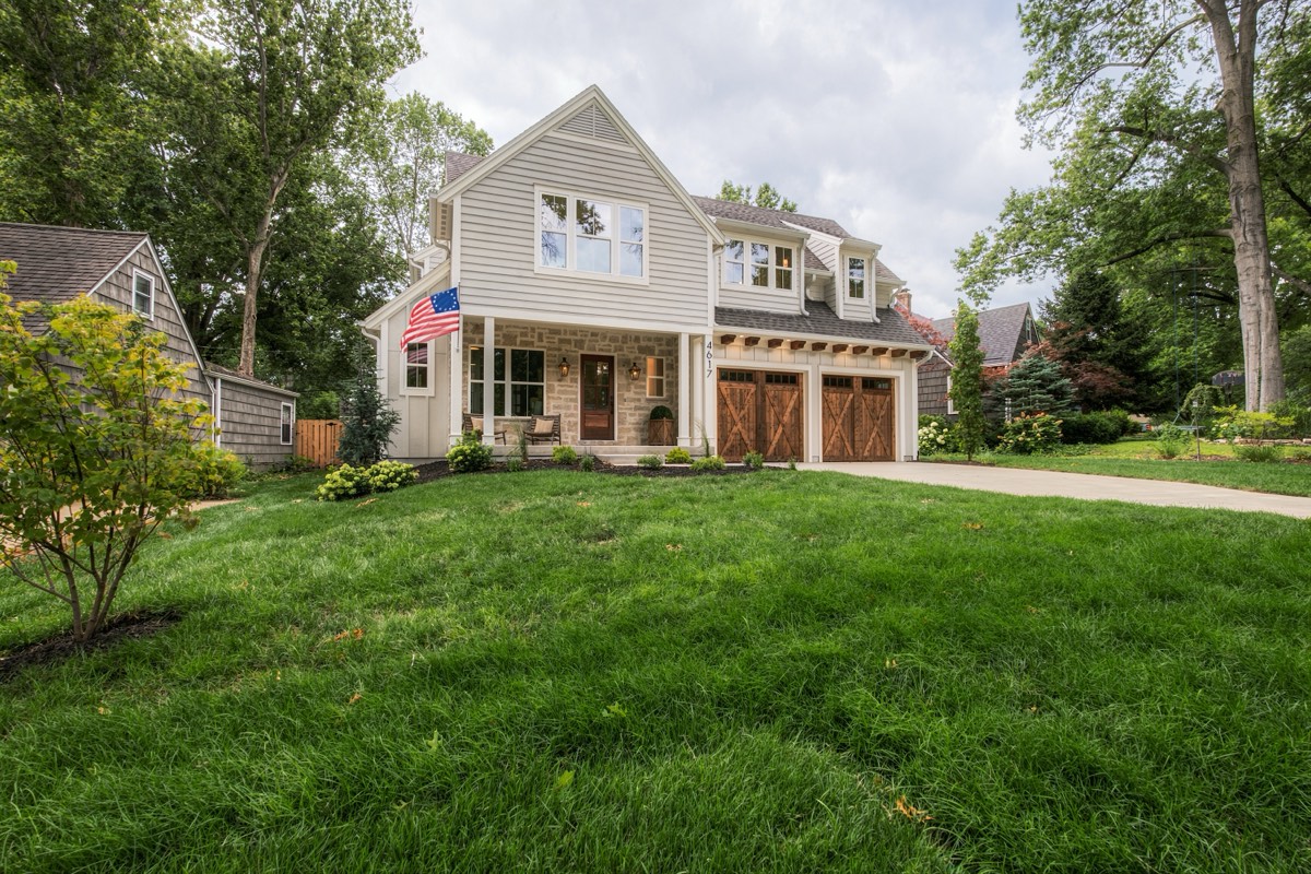 White farmhouse exterior with a covered porch and carriage-door garage