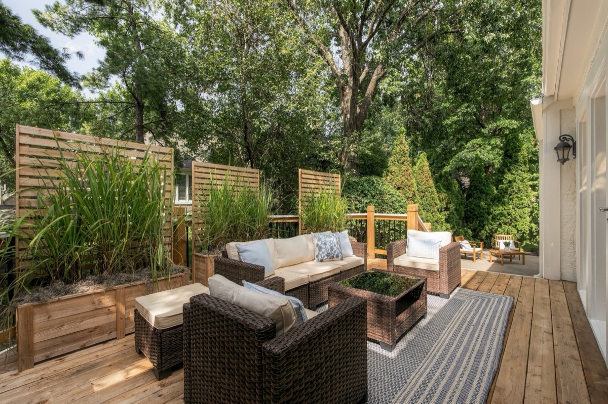 Cedar deck with woven outdoor seating framed by mature trees